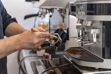 Ein Barista bereitet an einer Siebträger Kaffeemaschine einen Espresso oder Cappuccino zu  