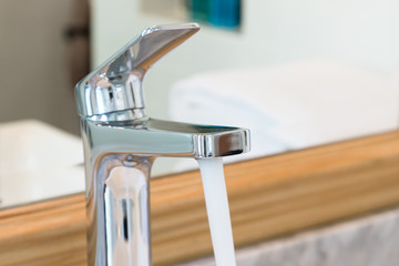 Modern style tap at sink in bathroom pouring water