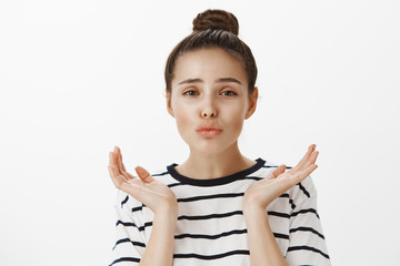 Girl feeling pretty looking in mirror. Portrait of good-looking girly woman with feminine face, folding lips and holding palms near head, applying makeup while standing over white background