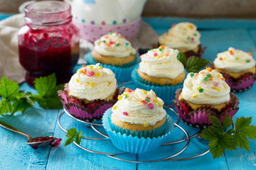 Birthday cupcake with buttercream icing and raspberry jam on a wooden table.