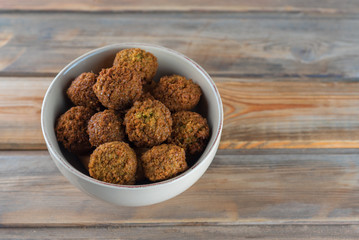 Falafel balls in a ceramic bowl on a wooden background. Falafel is a traditional Middle Eastern food, commonly served in a pita.