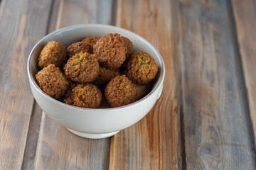 Falafel balls in a ceramic bowl on a wooden background. Falafel plays an iconic role in Israeli cuisine and is widely considered to be the national dish of the country.