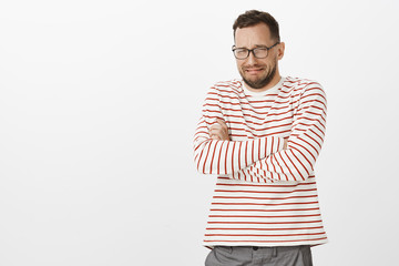 Brokenhearted miserable adult boyfriend in glasses, crossing hands on chest and crying, being...