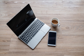 Silver color laptop with smartphone and  coffee cup on office wooden table