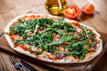 Pizza with chicken, arugula, cheese and onions on wooden rustic table. Top view.