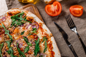 Pizza with chicken, arugula, cheese and onions on wooden rustic table. Top view.