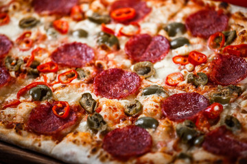 Delicious Pepperoni Pizza with salami, pepper and olives on rustic table. Top view. Toning.