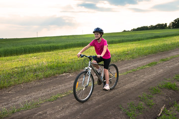 Sporty girl with bicycle in green field.