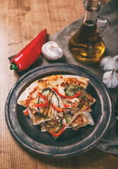 Sliced pizza with chicken, zucchini, eggplant, pepper, cheese and mushrooms on the plate vintage. Top view. Toning.