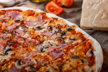 Pizza with ham, cheese, mushrooms and tomato sauce on wooden rustic table. Top view.