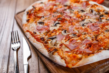 Pizza with ham, cheese, mushrooms and tomato sauce on wooden rustic table. Top view.