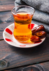 A glass of black tea and dates on a saucer