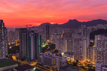 Naklejka premium Kowloon Residential Building and Urban Skyscrapers Under Mountains Lion Rock Summer Sunset Landscape with Dramatic Sky