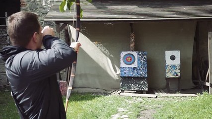Close up shot of archer with strong hands bending mechanic bow arrow concentrating on target