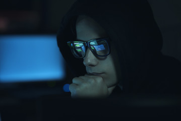 Hacker hiding in the dark and working with computers
