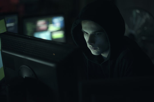 Hacker hiding in the dark and working with computers