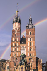 Fototapeta na wymiar The main square of Krakow with the St Mary Basilica after the rain, against the two rainbow and the purple sky
