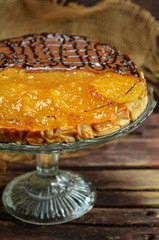 Cheesecake with orange jelly and caramel on a glass plateau