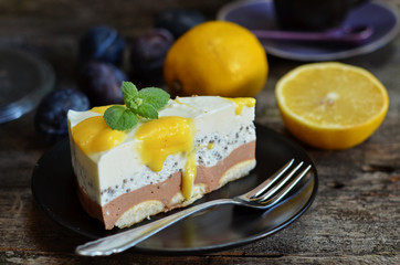 A piece of cold cheesecake with chia on a black saucer. Lemons on a wooden background