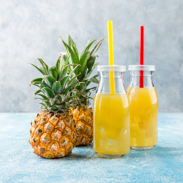 Fresh pineapple juice and ripe pineapple on grey background