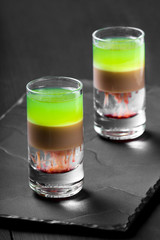 Alcoholic cocktail in shot glass on stone slate background. Summer drinks.