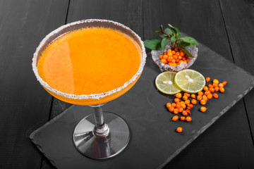 Alcoholic cocktail with sea buckthorn in a glass on dark background. Summer drinks and cocktails.
