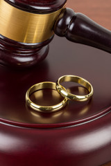 Wooden judge gavel and golden rings divorce concept