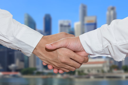 Business people shake hand in front of financial district