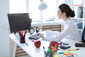 Young girl in the office working with documents at the computer.