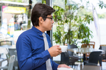 Asian businessman drinking coffee thinking of plan