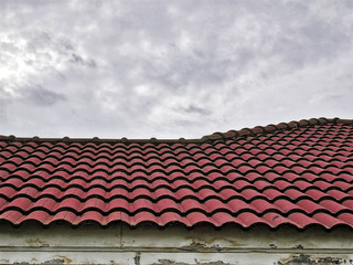 Fototapeta premium Old Red Tiled Roof Against Cloudy Sky