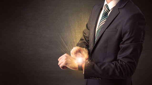 Businessman wearing smartwatch with shiny rays on it. - Powered by Adobe
