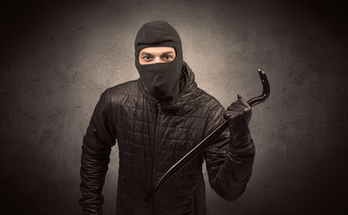 Burglar standing in black clothes and balaclava on his head.