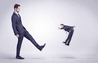 Big man in suit kicking out little himself out with simple white wallpaper
