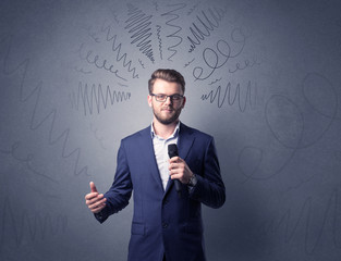 Businessman speaking into microphone with scribbles over his head 