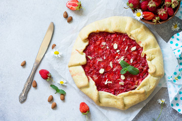 Fresh homemade strawberries galette with nut cream on a gray stone or slate background. Top view flat lay background. Copy space.