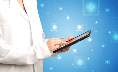 Female doctor holding tablet with blue background and crosses