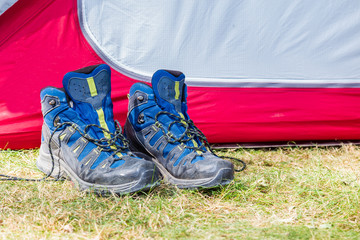 Walking boots with socks beside a tent on a campsite