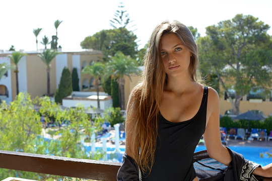turista mujer joven atractiva de aspecto nordico posiblemente sueca con pelo largo formando una hermosa melena  con bañador negro en la terraza de un hotel  en España durante las vacaciones de verano