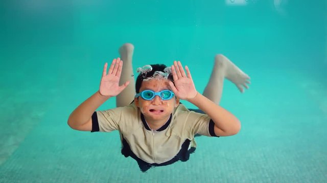 Happy preteen boy swimming and waving hands underwater in the pool. Shot in 4k resolution