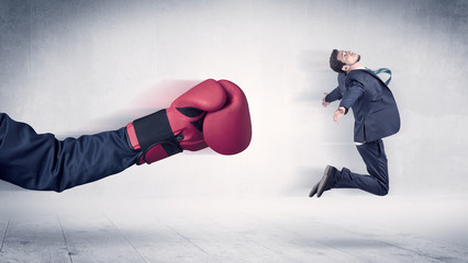 Huge Boxing Gloves punches innocent businessman concept
