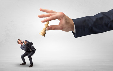 Big hand holding chessman and down little afraid businessman concept in a light space
