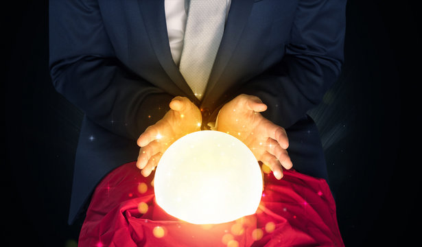 Gorgeous businessman sitting with sparkling magic ball in his lap
