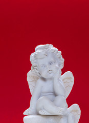 Figurine Of Baby Angel On Red Background