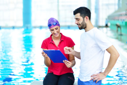 Swimmer and coach discussing by the pool at leisure center