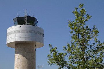 Tower eines Flughafens vor einem blauen Himmel mit einem gr&uuml;nen Baum