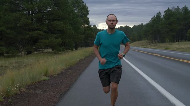 A man running down a country road on a rainy morning