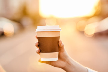 young girl holding paper Cup with hot coffee at sunset