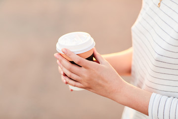 young girl holding a paper Cup of hot coffee