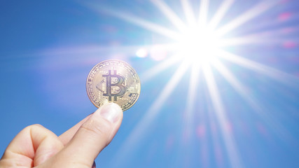 Bitcoin Münze wird in die Sonne gehalten